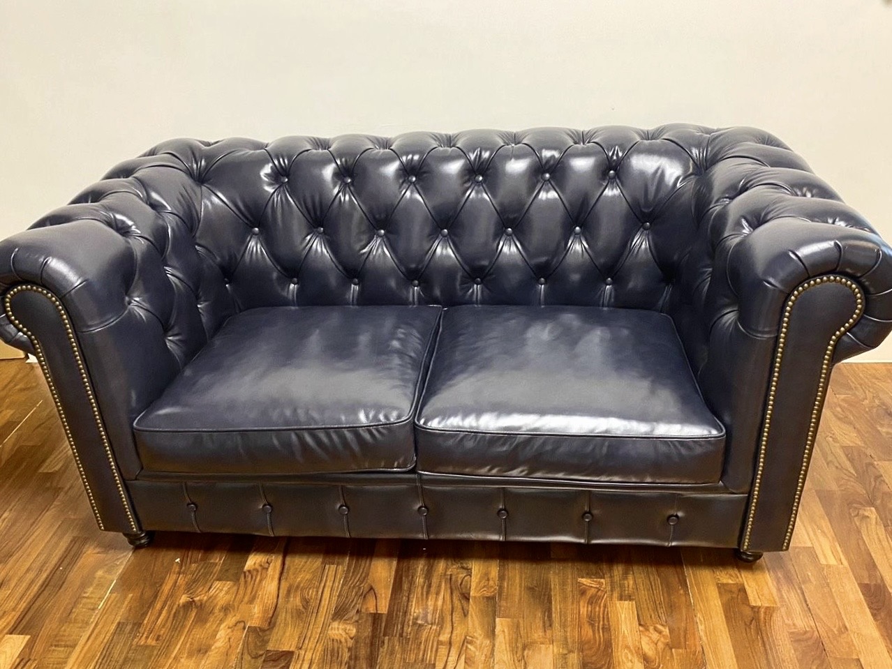 Chesterfield Style B 頂級油蠟黃牛皮沙發側視圖，完美呈現深炭藍皮革原生紋理、純手工深層菱格拉扣工藝，以及邊緣精準俐落的黃銅鉚釘收邊細節。